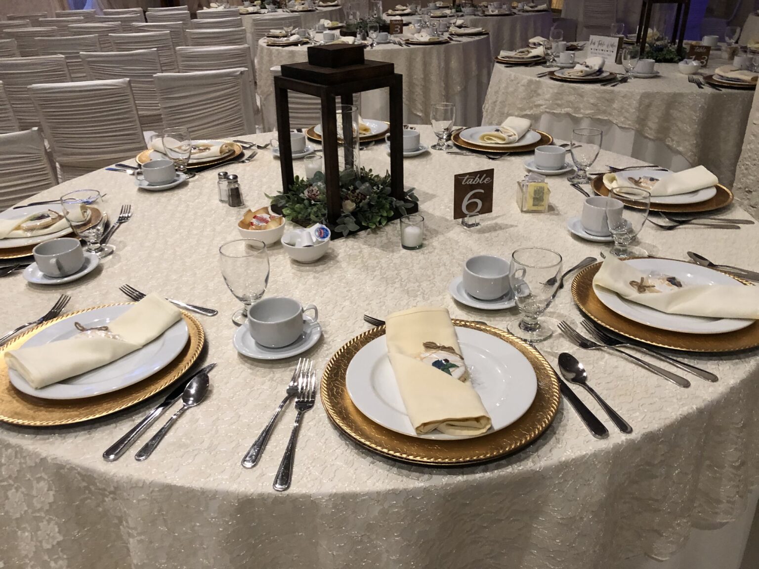 A round table set with ivory linen and gold chargers at Everest Convention Centre