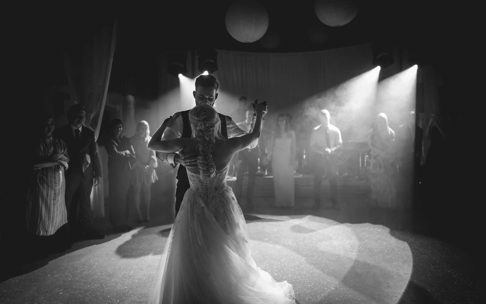 A couple dancing in front of a cheering crowd at a reception